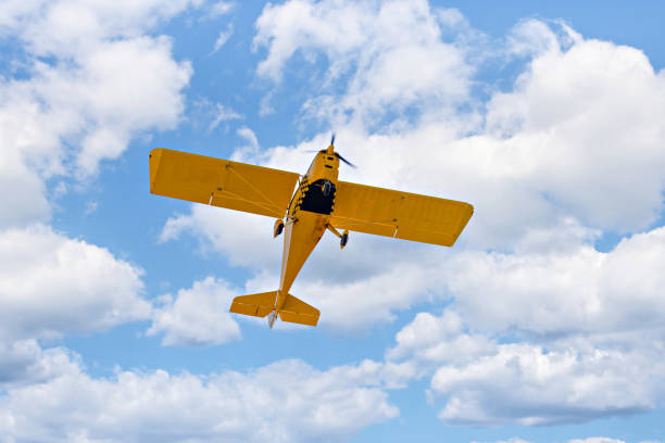 istock Light aircraft flying over blue sky 1472035065