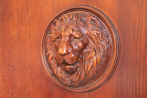 lion wooden head decor on front door. Bas-relief close-up.