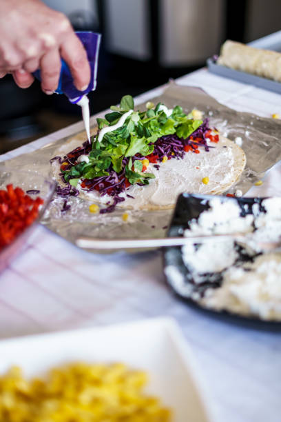 A young woman is preparing Mexican food with vegetables and meat.