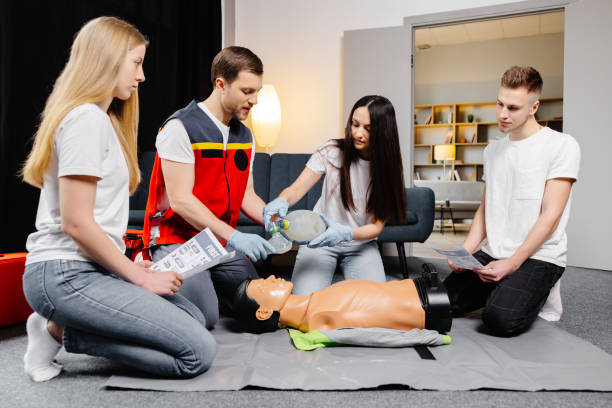 istock Group of people learning how to make first aid heart compressions with dummies during the training indoors 1472041194