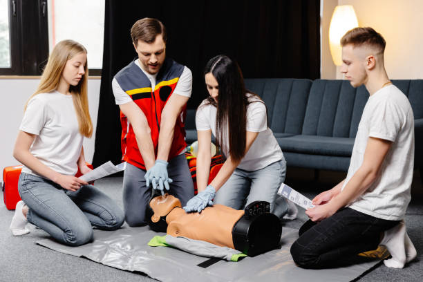 istock Group of people learning how to make first aid heart compressions with dummies during the training indoors 1472041197
