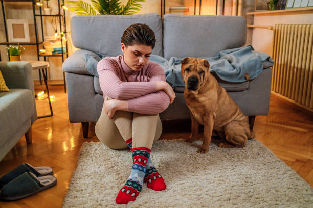 mujer triste en casa con un perro a su lado - pessimist women one person caucasian fotografías e imágenes de stock