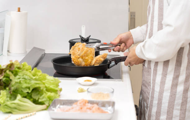 istock Asian man grilling chicken on a frying pan 1472049116