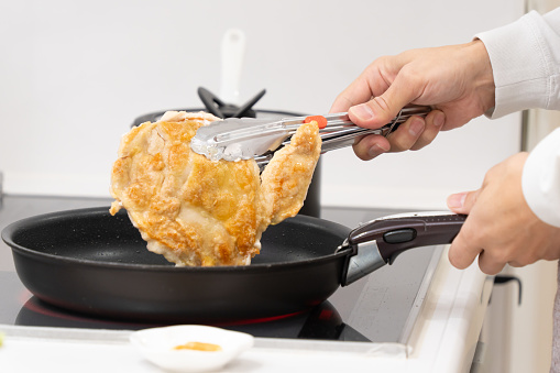 Asian man grilling chicken on a frying pan
