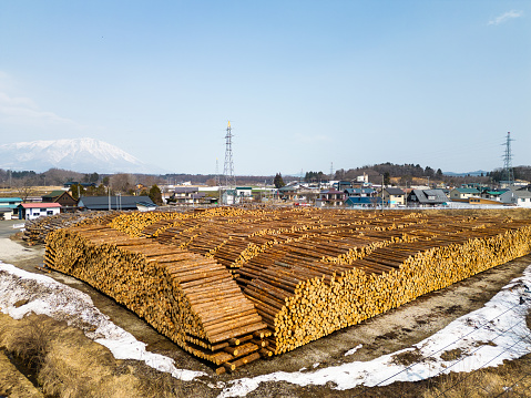 A drone point of view of a large field with stacked piles of cut logs ready to be processed.