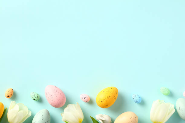 istock Happy Easter card with colorful Easter eggs and white tulips on pastel blue background. Flat lay, top view. 1472051094