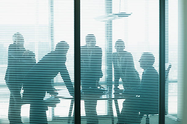 Silhouette of business people leaning on table in conference room  window blinds photos stock pictures, royalty-free photos & images