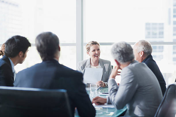 Smiling businesswoman leading meeting in conference room  mature businessman stock pictures, royalty-free photos & images
