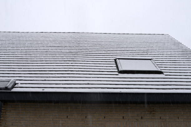 Saddle roof detached house in wInter. Black baked earth roof tiles slope 45 degrees covered with a layer of snow