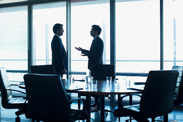 бизнесмен, говорящий лицом к лицу в конференц-зале - business person silhouette back lit discussion стоковые фото и изображения