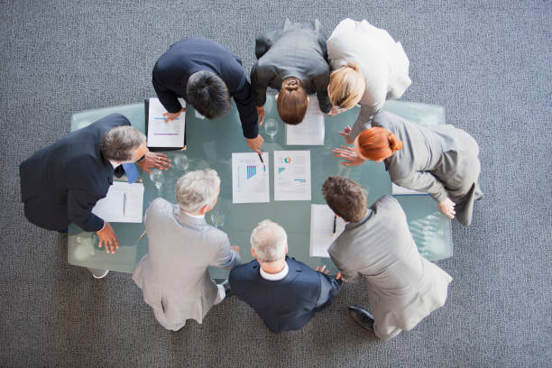 Business people huddled around paperwork on table  Strategies stock pictures, royalty-free photos & images