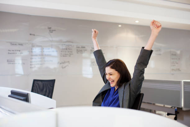 Enthusiastic businesswoman with arms raised in office  one mid adult woman only stock pictures, royalty-free photos & images