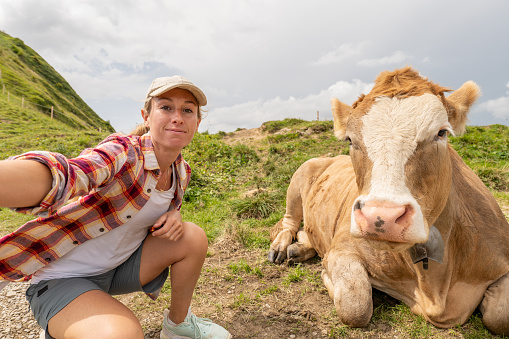 She smiles at the camera,  cattle cow beside her
Appenzelerland canton, Switzerland