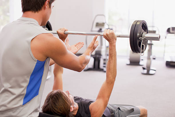 mann beobachten freund lifting langhantel im fitnessraum - spotting stock-fotos und bilder