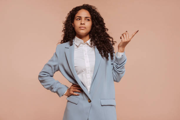 istock Young businesswoman points away with index finger 1472057418
