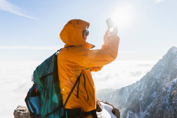 istock Hiker with yellow rain jacket using smartphone in the high mountains 1472059508