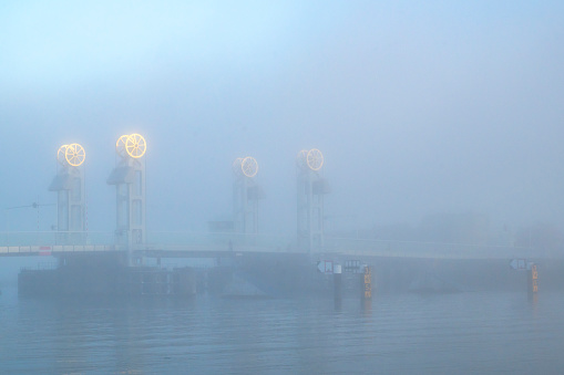 City bridge over the river IJssel in Kampen, Overijssel, The Netherlands during a foggy autumn morning.