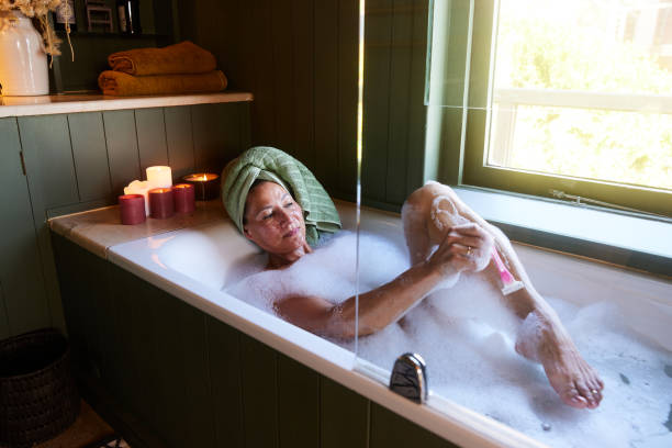 istock Smiling mature woman shaving her legs while taking a bath 1472060831