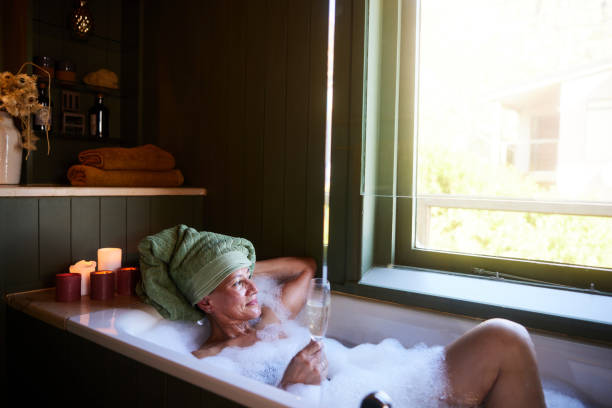 istock Smiling mature woman drinking champagne while soaking in her bathtub 1472060883