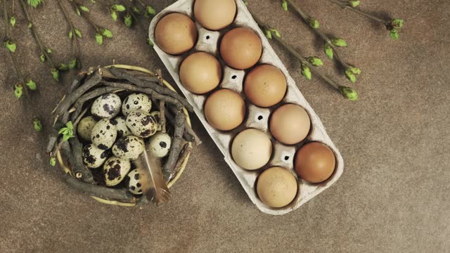 Easter concept background. Greeting card with quail eggs in the nest, chicken eggs, twigs with green leaves and feathers on wooden background rotating. Happy Easter holiday rotate