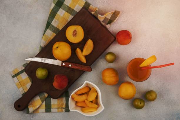 白いボウルに桃のスライスとナイフを持つ木の台所の板に新鮮な黄色の桃の上面図 - fruit vegetable fruit bowl peaches ストックフォトと画像