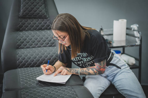 istock Young tattoo artist signs or drawing copyright agreement at work 1472066173