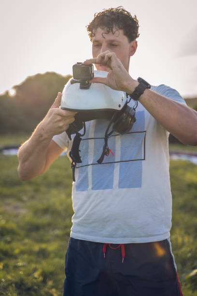 Young man mounts the action cam on the helmet, before starting a flight session, with the paramotor.
