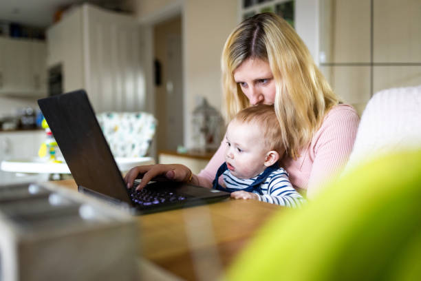 istock Woman and baby boy looking at computer at home 1472067911