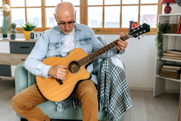 istock Senior man playing guitar at his apartment 1472073456