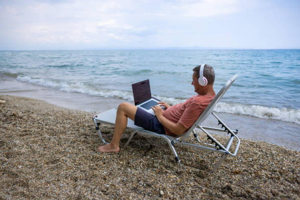 istock During his vacation, Caucasian man working on laptop on the beach 1472075102