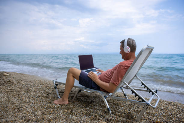 istock During his vacation, Caucasian man working on laptop on the beach 1472075134