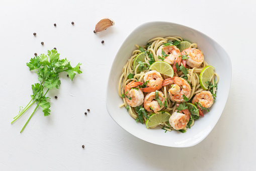 Pasta spaghetti shrimp lemon coriander in white bowl isolated on white background close up, top view, food concept.