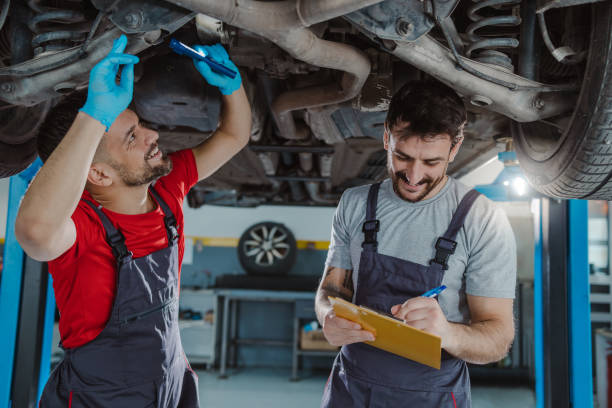 istock Auto mechanics examining underside of car 1472076723