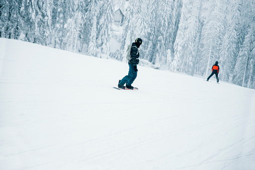 Man snowboarding in mountains at ski resort. Copy space