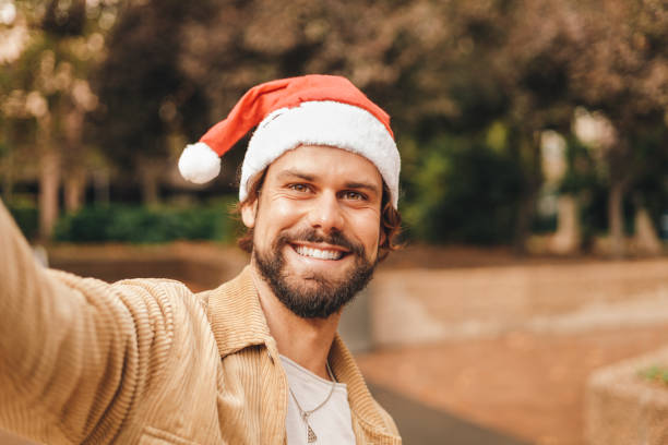 istock caucasian millennial man taking selfie with santa hat, camera pov 1472077913