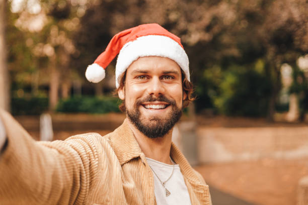 istock caucasian millennial man taking selfie with santa hat, camera pov 1472077945