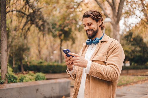 z gen caucasian man using cellphone in park. High quality photo.