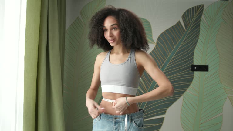 Happy Woman After Weight Loss. Mixed race slim female wearing oversized jeans. Successful weight loss.