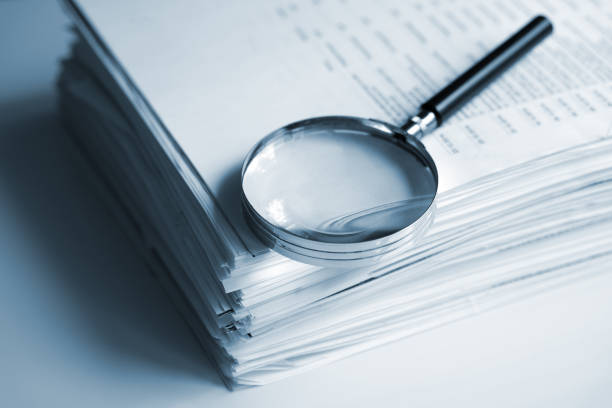 Magnifying glass on a stack of documents stock photo