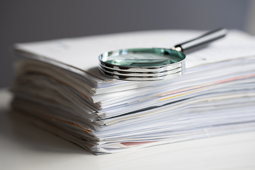 Magnifying glass on a stack of documents