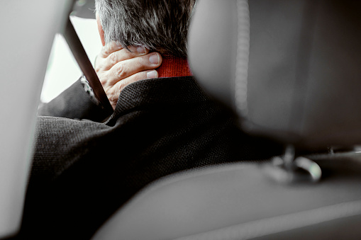 Rear view of a man having neck pain while driving a car