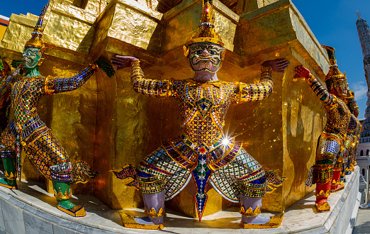 Wat Phra Kaew in Bangkok detail of one of the golden chedi, showing the supporting giants around the base.he color and clothing of these figures identify them with a particular character