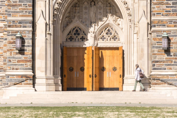 Woman at entrance to Duke University Chapel, heavy, wooden double doors. stock photo
