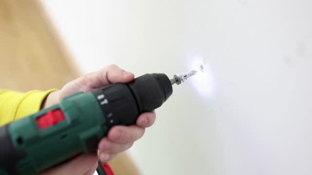 Drilling screws in wall of apartment with cordless drill