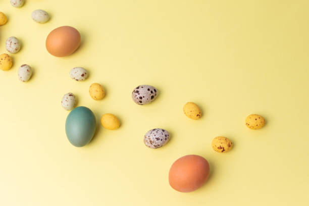 istock Colored eggs of different sizes on a yellow background. Symbol of the Easter holiday. Easter background 1472093640