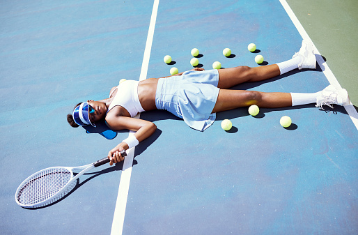 Tired, tennis and sad black woman on a court after a game, sports fitness and training fail in London. Depression, exercise and African tennis player on the floor after a loss in a professional match