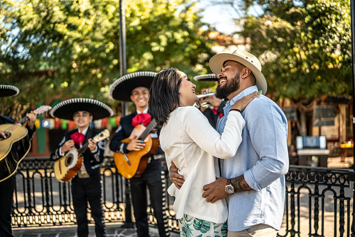 Married couple dancing to traditional mariachi music outdoors