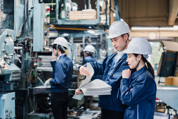 大量の紙文書をチェックする工場スタッフ - 材料 開発 ストックフォトと画像