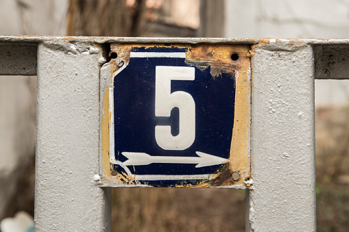 Weathered grunge square metal enameled plate of number of street address with number 5