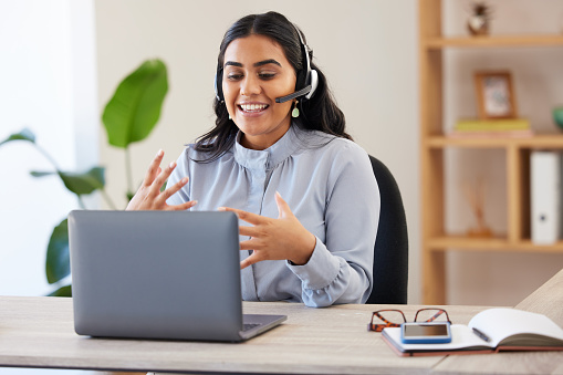 Video call, laptop and seminar with a business indian woman meeting online while sitting in her office at work. Remote work, headset and communication with a female employee talking in a webinar